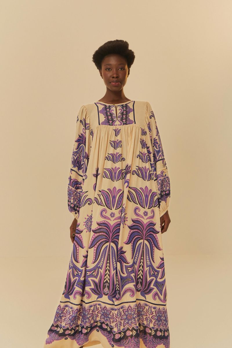 Vestido largo estampado con detalles florales y geométricos en tonos morado y beige, visto desde el frente.