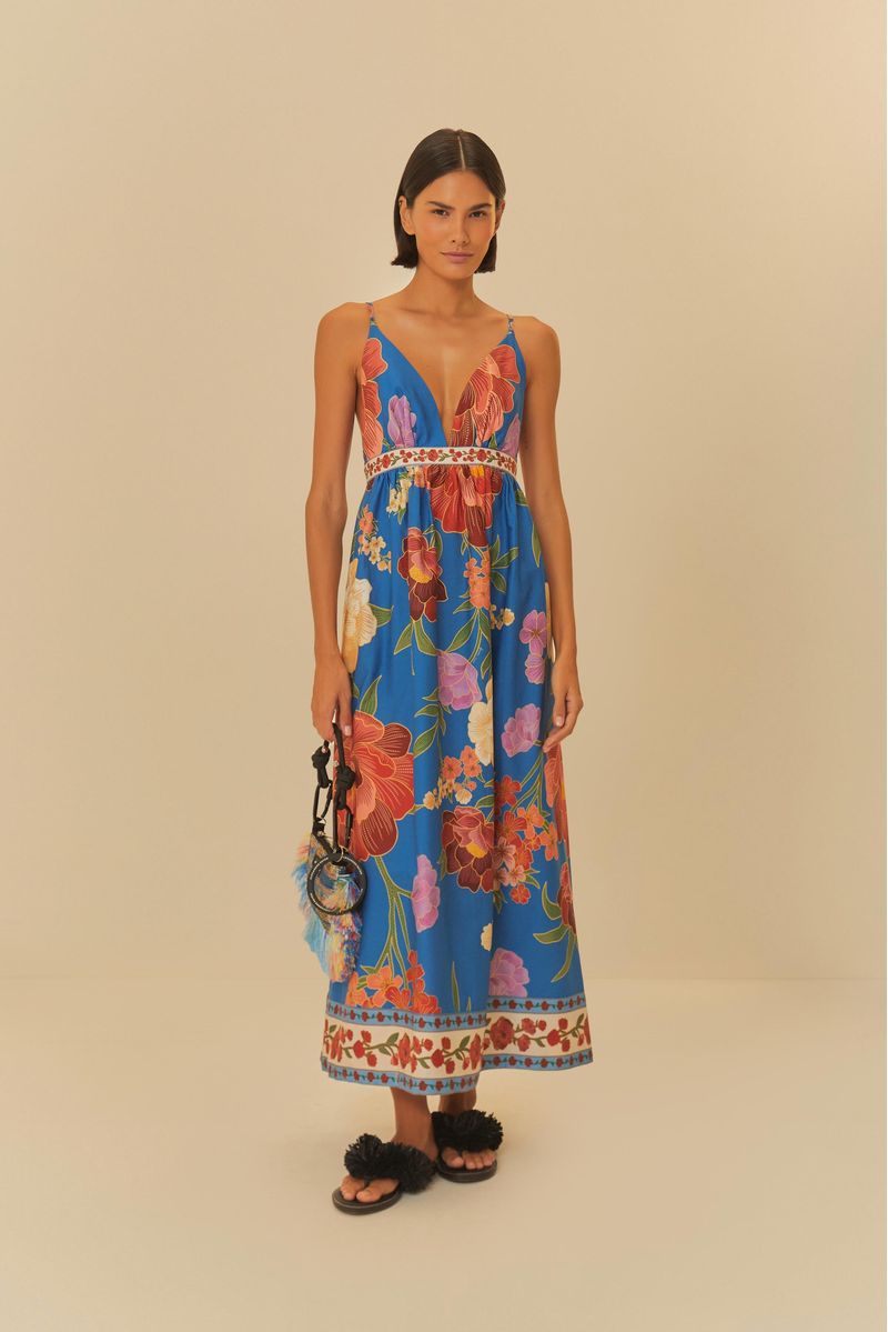 Vista frontal del vestido largo estampado con fondo azul y flores grandes, destacando el escote profundo y la cintura ajustada.
