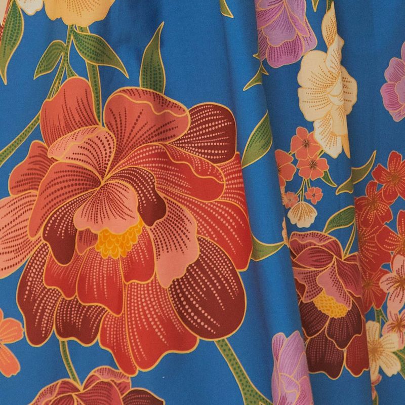 Vista completa del vestido largo estampado con fondo azul y borde decorado con patrón floral, combinado con sandalias negras.