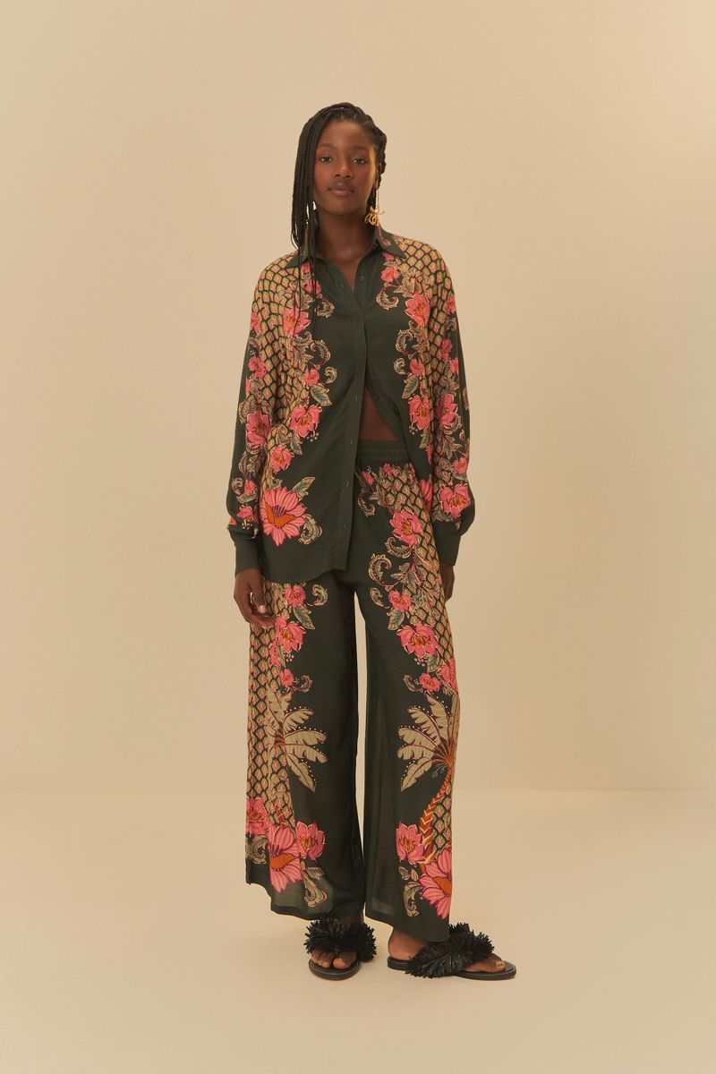 Modelo de pie usando conjunto de camisa y pantalón estampados con diseño botánico, en fondo neutro.