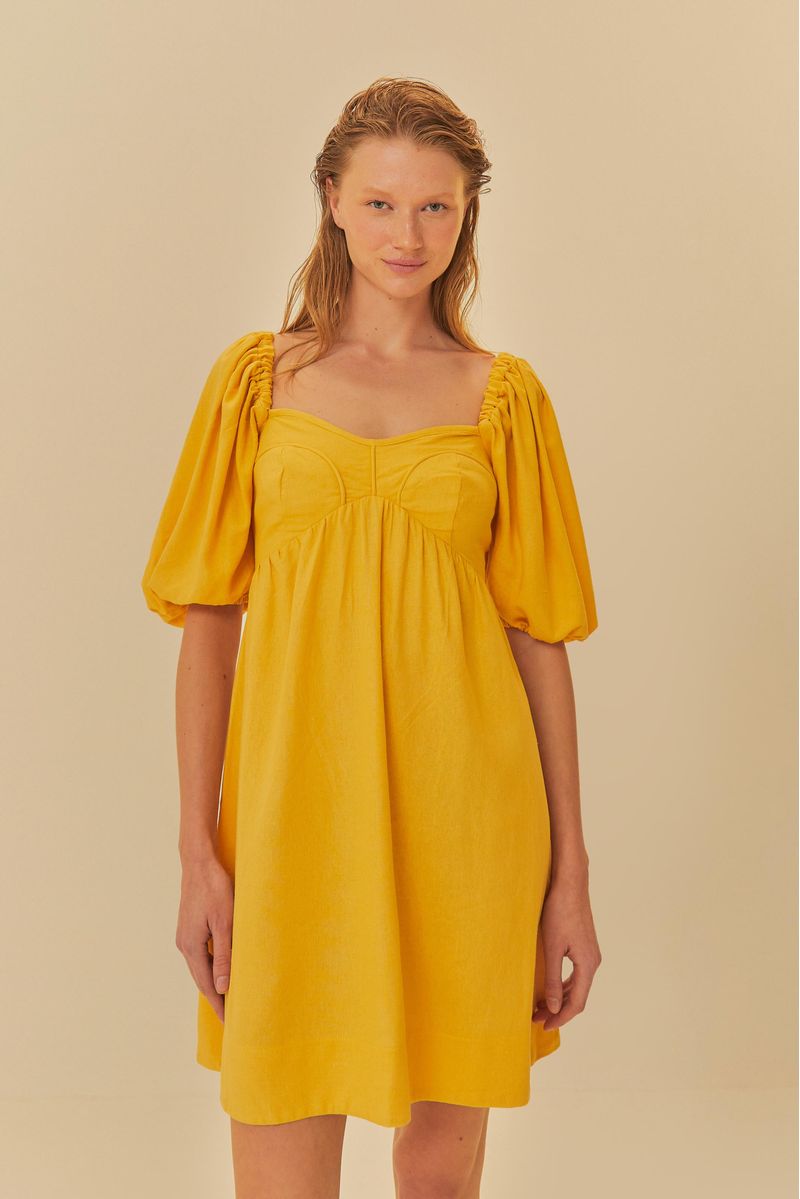Detalle-del-vestido-corto-amarillo-con-mangas-abullonadas-y-escote-corazon-enfocando-el-corpiño.