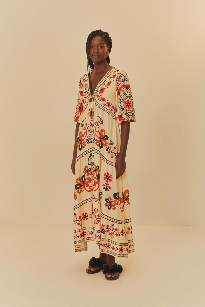 Imagen de una modelo de pie usando un vestido largo estampado con motivos florales y geométricos, mostrando el largo y la caída.