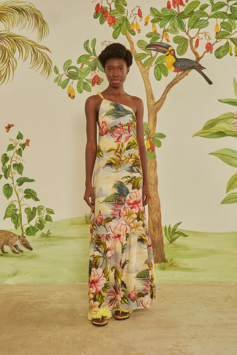 Modelo usando el vestido largo con estampado tropical, en un escenario con elementos naturales.