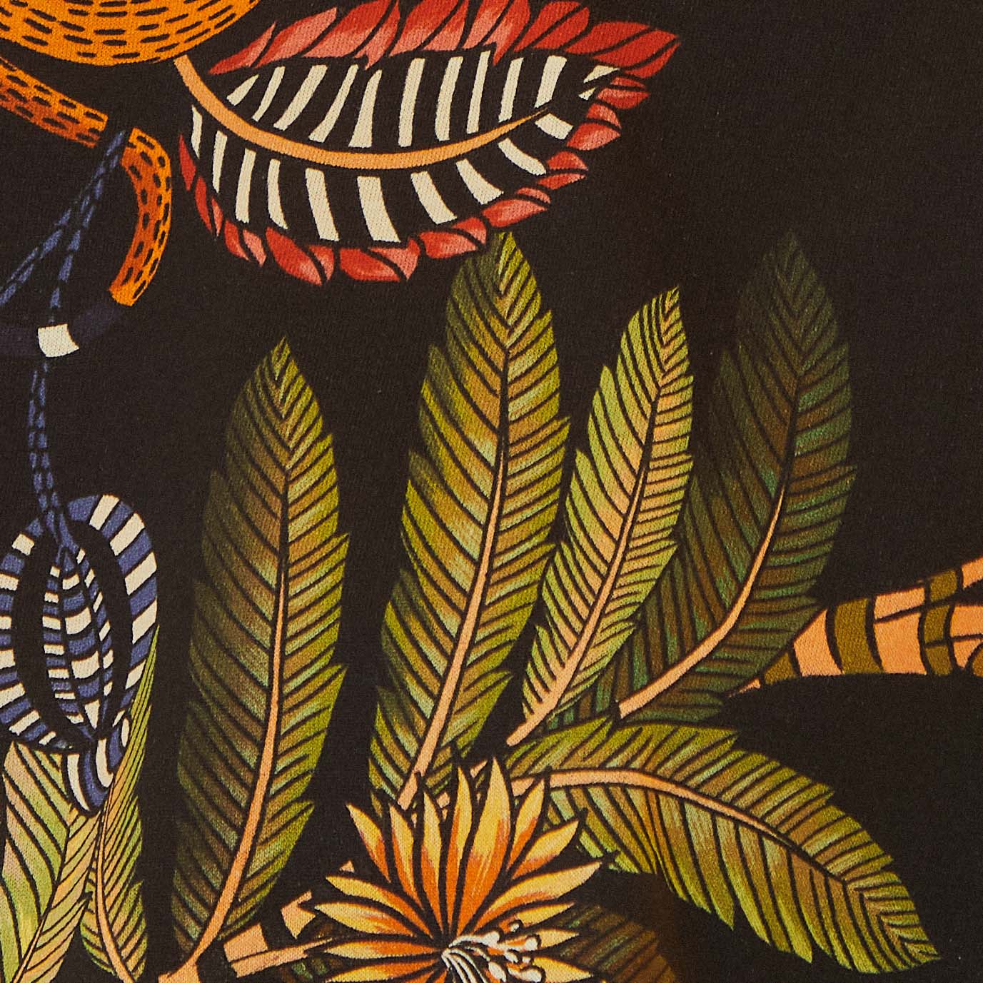 Primer plano del estampado tropical en la camiseta cropped, mostrando detalles de fauna y flora.
