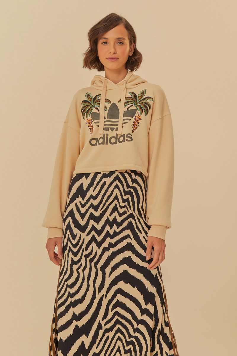 Modelo vistiendo falda midi con estampado de cebra y sudadera Adidas.