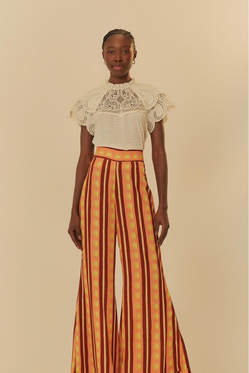 Modelo-usando-pantalon-largo-estampado-con-rayas-verticales-en-tonos-de-naranja-y-rojo-vista-frontal.