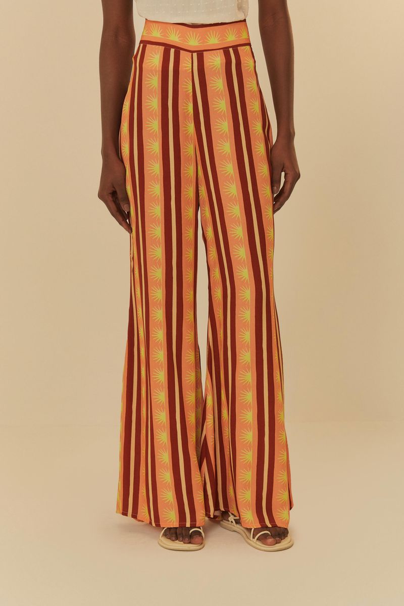 Modelo-usando-pantalon-largo-estampado-con-rayas-verticales-en-tonos-de-naranja-y-rojo-vista-trasera.
