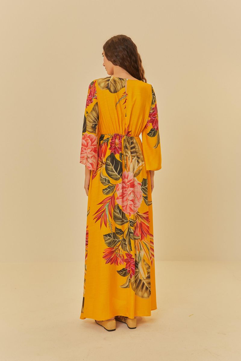 Vista trasera del vestido largo estampado floral con fondo amarillo, mostrando la caída y las mangas.