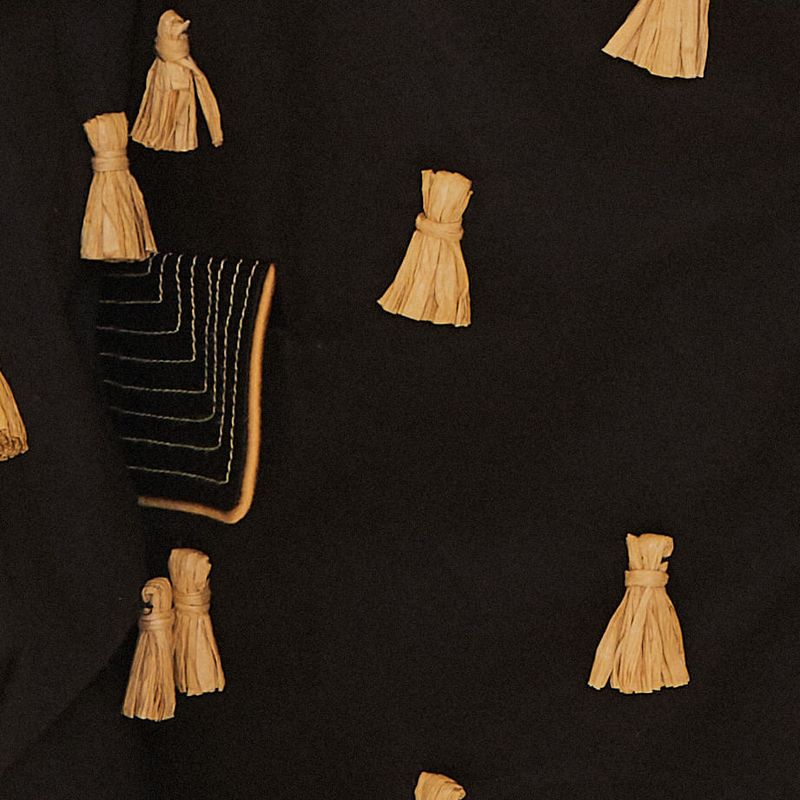 Detalle-del-bolsillo-del-blazer-negro-con-borlas-de-rafia.