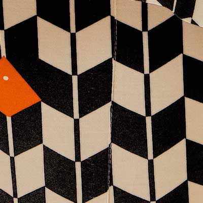 Primer-plano-del-estampado-geometrico-en-negro-y-beige-con-detalles-en-naranja-del-pantalon-largo.