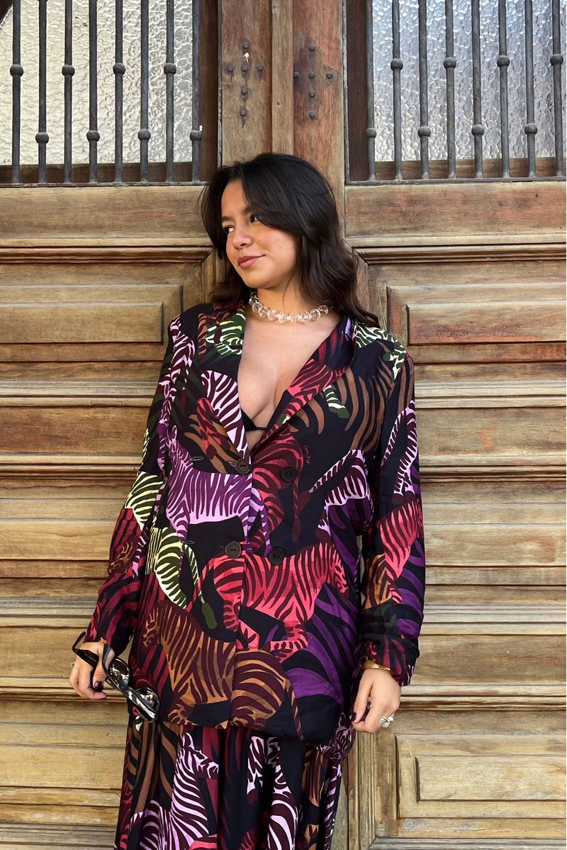Blazer-estampado-con-diseño-de-cebras-en-colores-vibrantes-mostrado-en-modelo-cerca-de-una-puerta-de-madera.