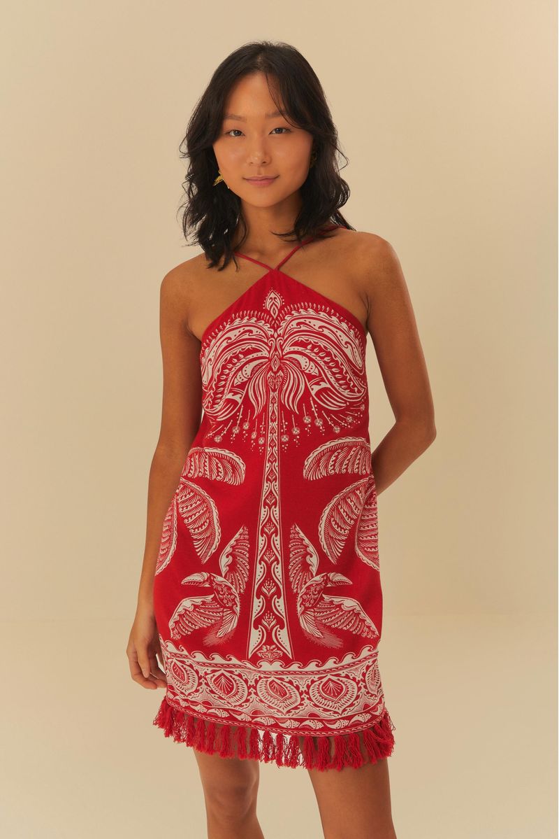Vestido corto estampado con palmeras sobre fondo rojo, con tiras finas y escote halter.