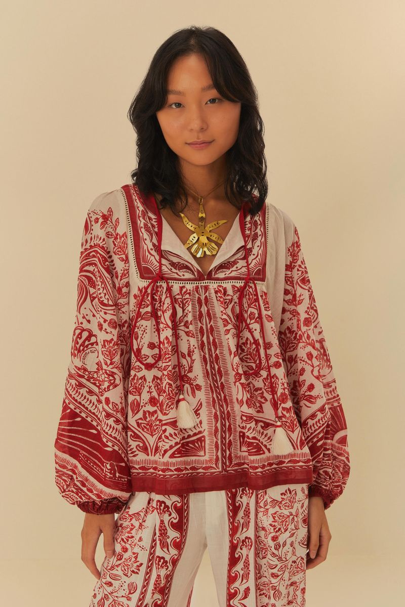 Blusa estampada con detalles florales en rojo y fondo beige, vista frontal.
