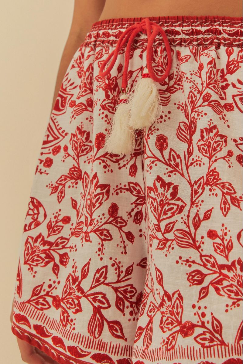 Vista frontal del short estampado floral rojo y blanco, destacando el patrón y los bolsillos.