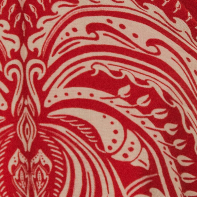 Detalle del estampado de palmeras en el vestido corto sobre fondo rojo.