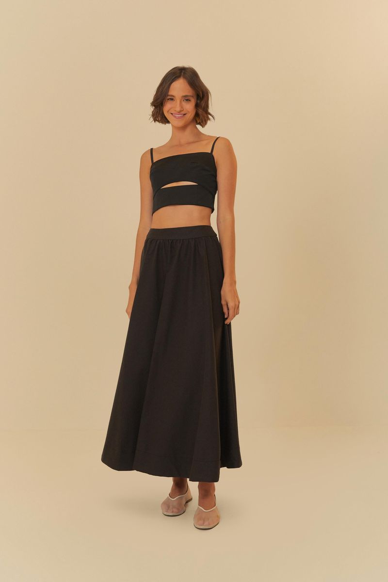 Modelo luciendo una falda amplia negra con un top negro, vista lateral.