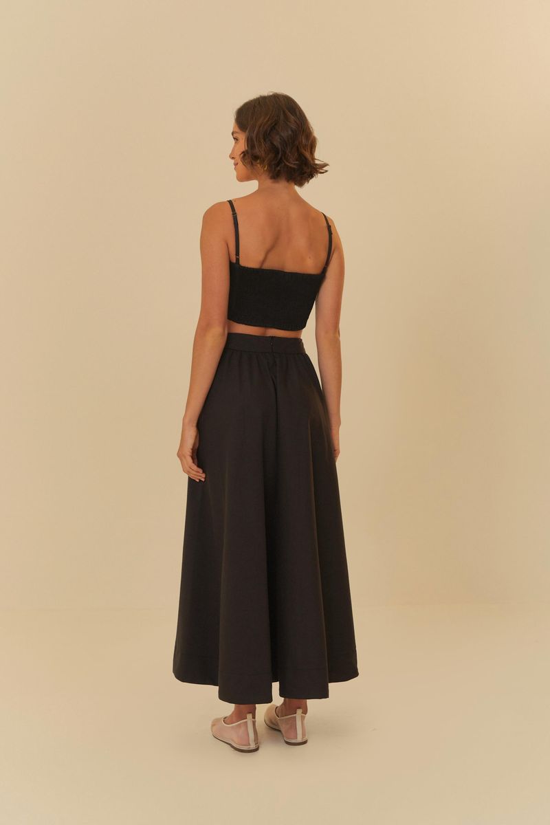 Modelo luciendo una falda amplia negra con un top negro, vista trasera.