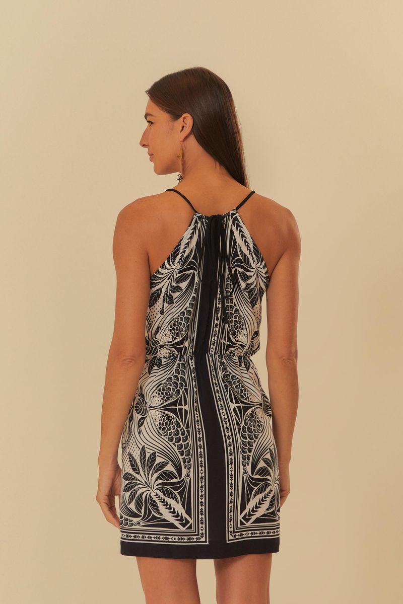Vista trasera del vestido corto con estampado botánico en blanco y negro, tirantes delgados y detalle fruncido.