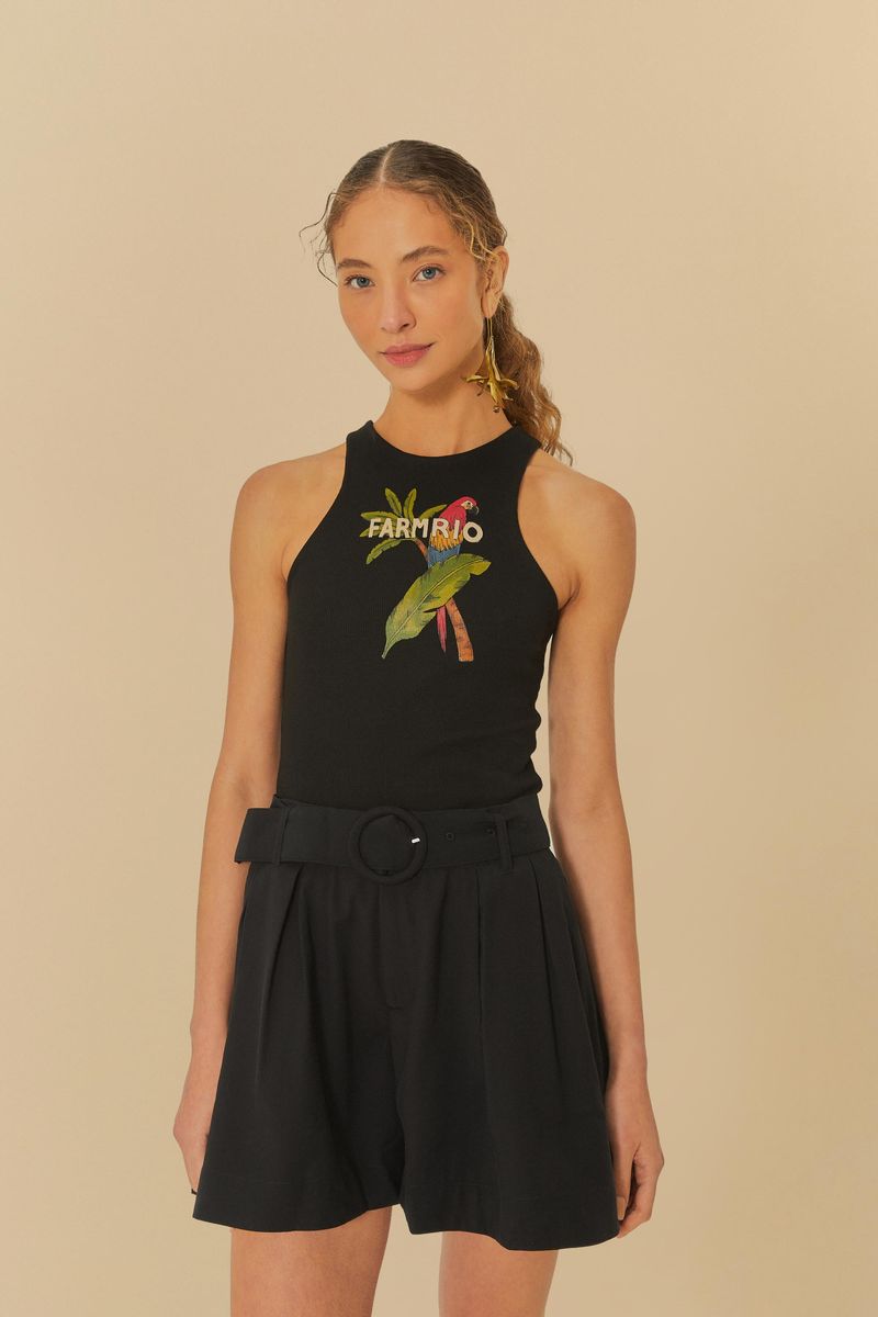 Modelo usando un short negro de sastrería con pinzas y cinturón ajustable, combinado con una blusa negra estampada.