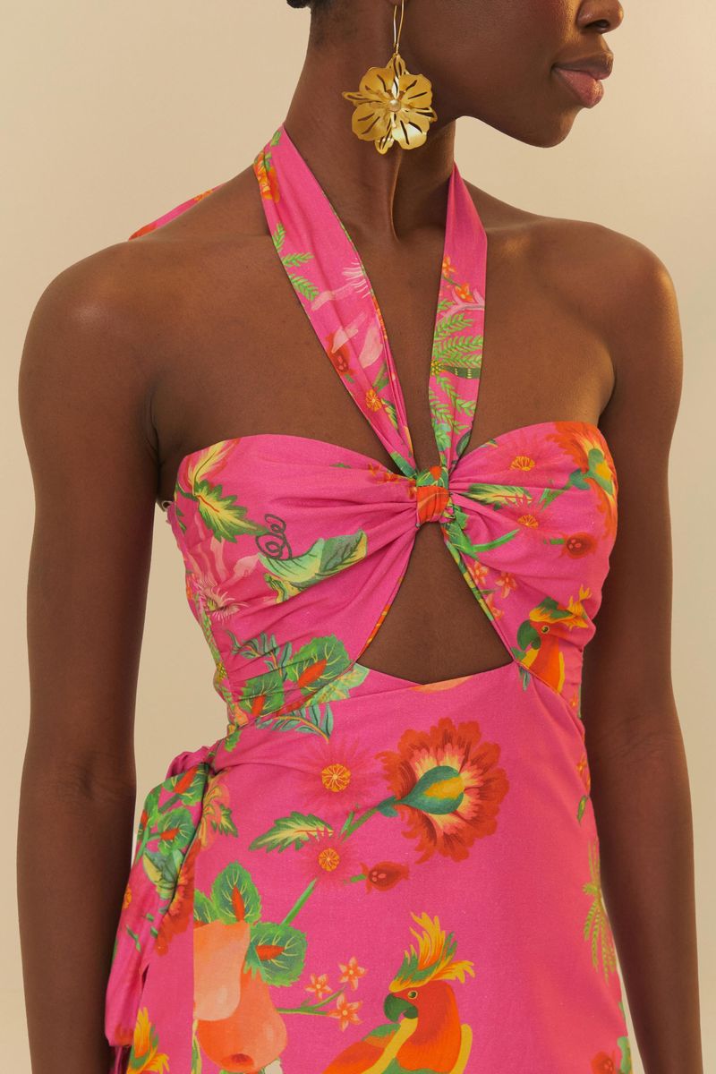 Vista trasera del vestido estampado con fondo rosa y detalles tropicales, mostrando el diseño del escote y la longitud cropped.