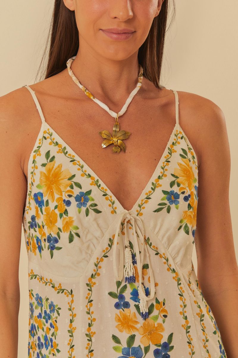 Primer plano del escote en V del vestido floral, destacando los tirantes finos y el estampado vibrante.
