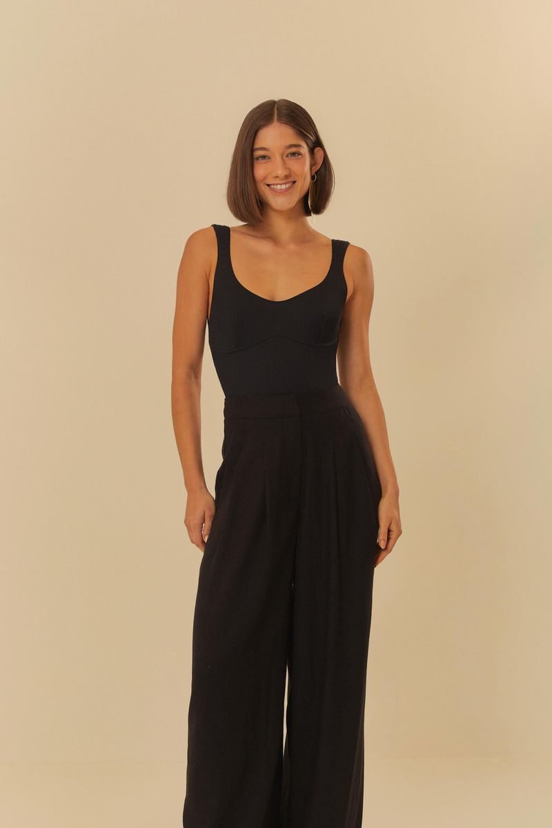 Modelo de frente usando pantalón negro con pinzas, destacando el ajuste en la cintura y piernas anchas