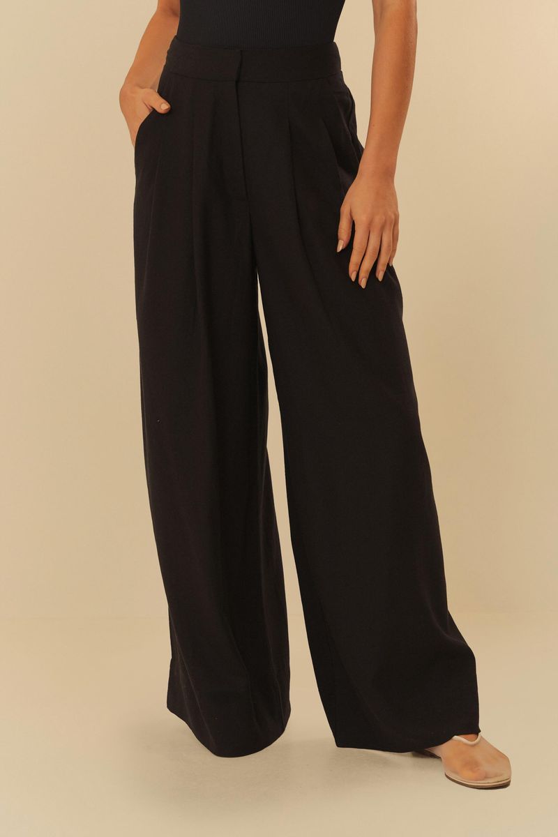 Detalle lateral del pantalón negro con pliegues y bolsillos.