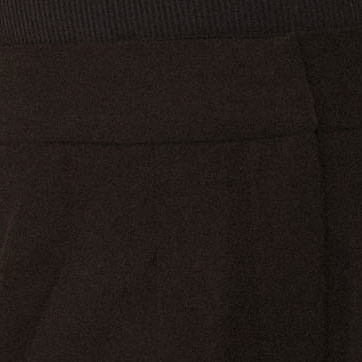 Detalle del tejido del pantalón negro con pliegues y bolsillos.