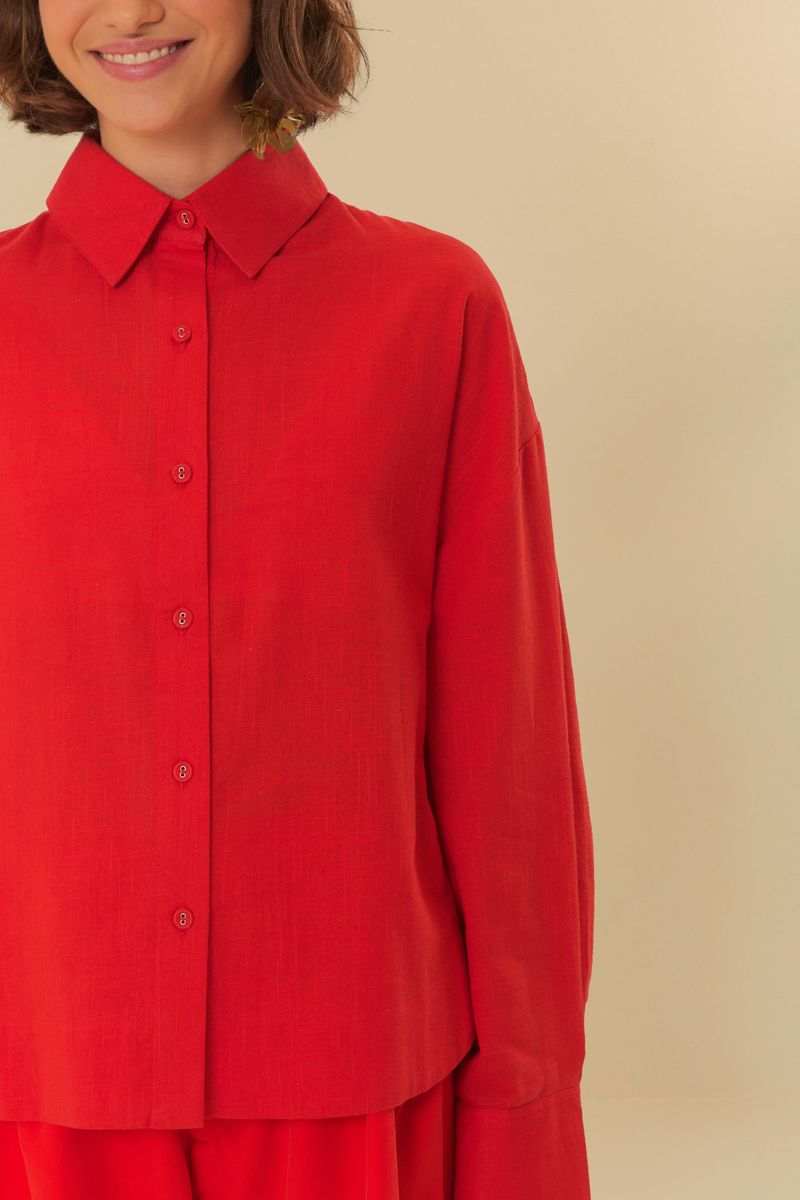 Detalle del cuello puntiagudo y cierre con botones de la camisa larga roja.