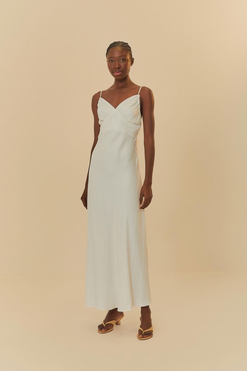 Vestido largo blanco con tirantes finos y escote cruzado, visto de lado.