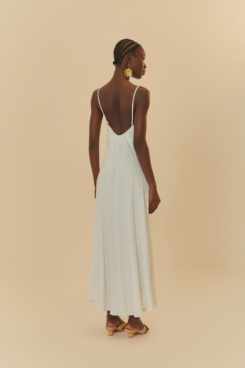 Detalle del escote cruzado del vestido blanco con tirantes finos.
