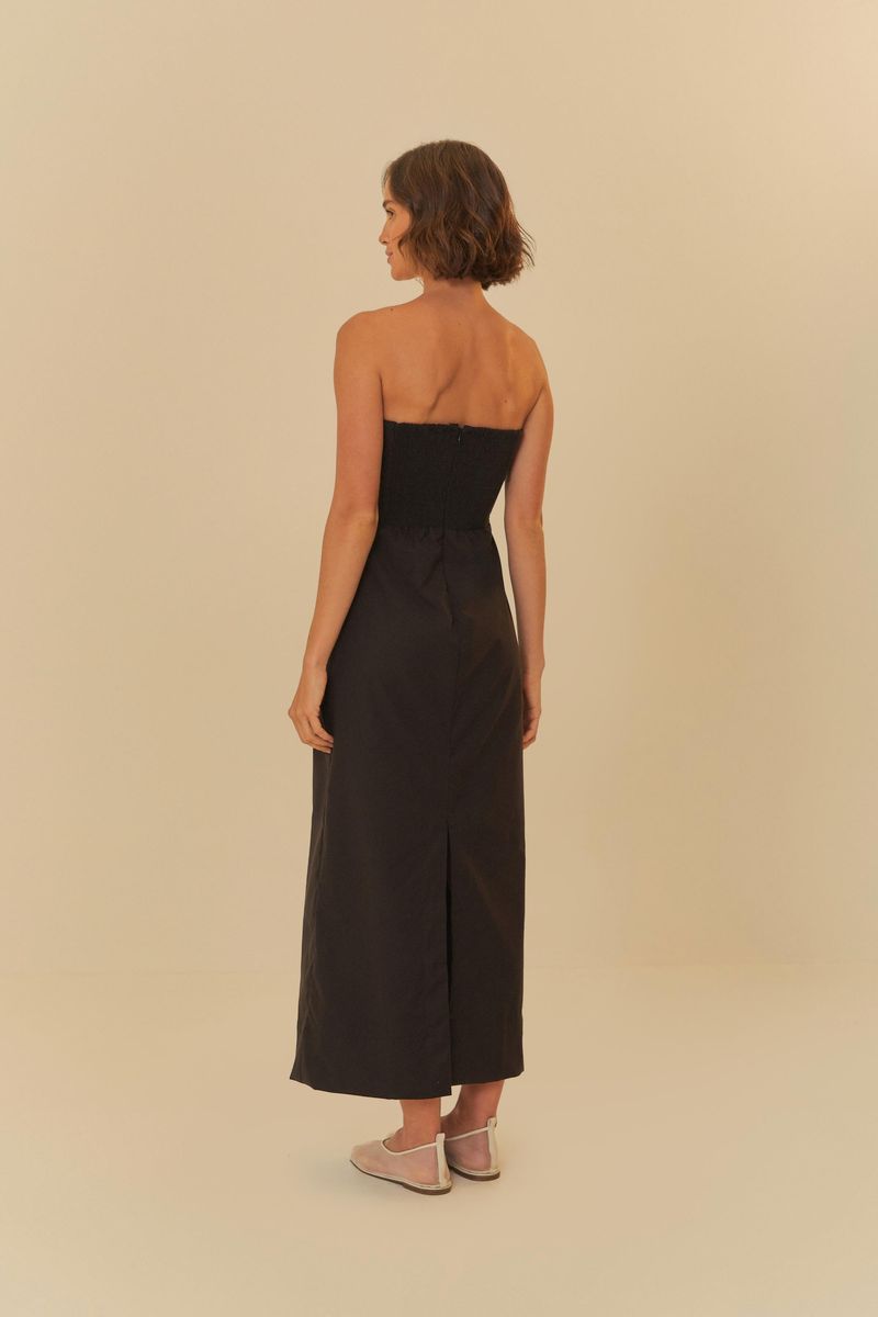Acercamiento al escote profundo del vestido negro recto.