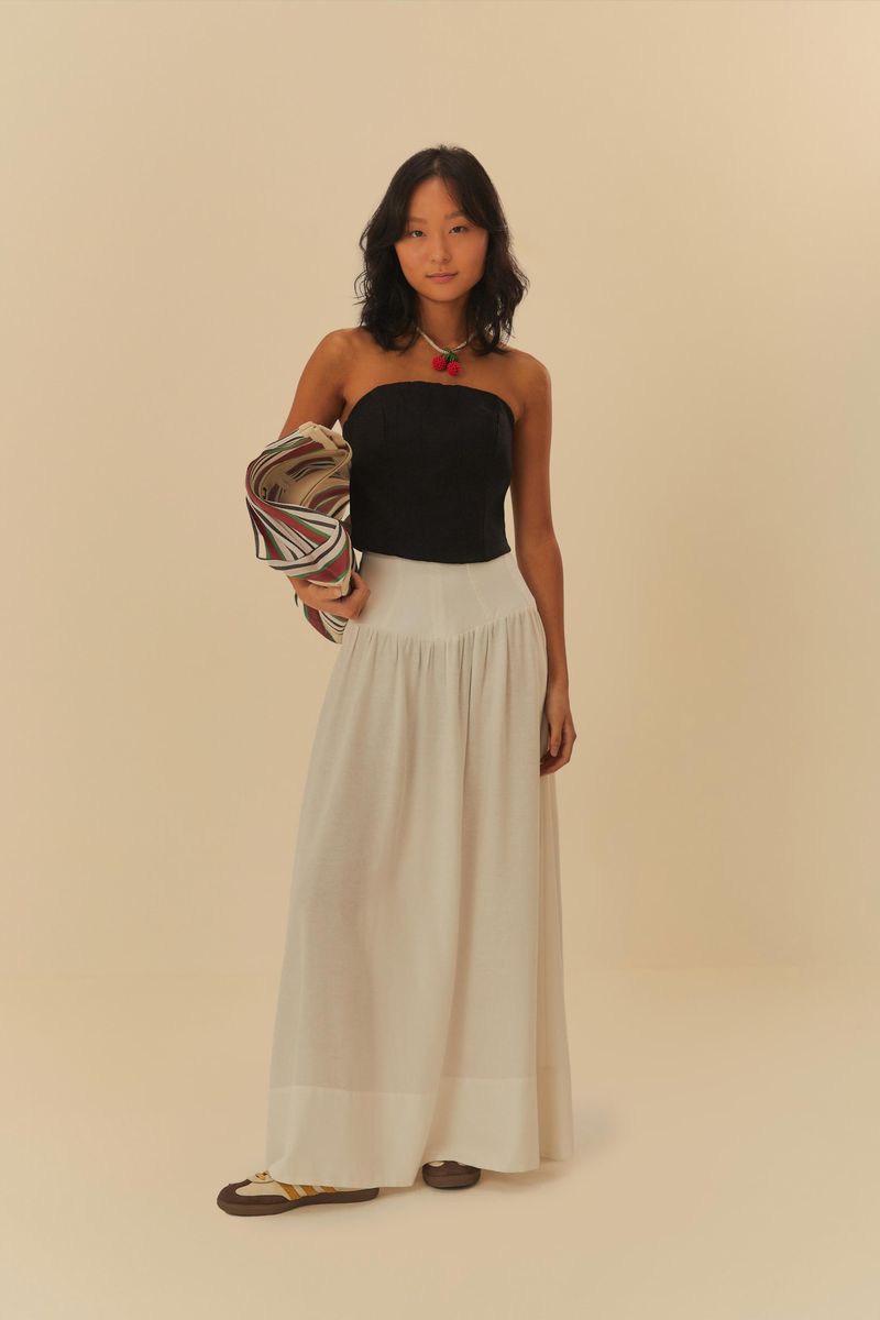 Blusa corset negra con pespuntes sin tirantes, combinada con falda larga blanca.