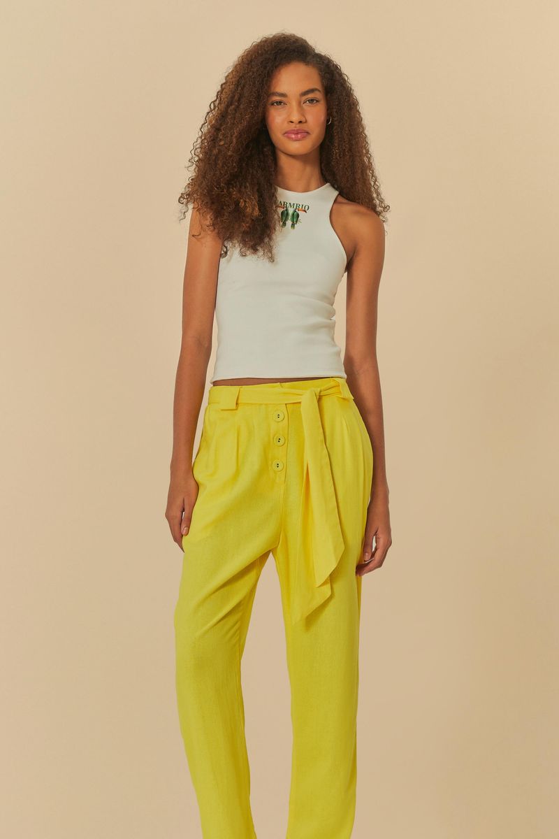 Modelo usando pantalón amarillo recto con cintura alta y bolsillos frontales, combinado con top blanco sin mangas.