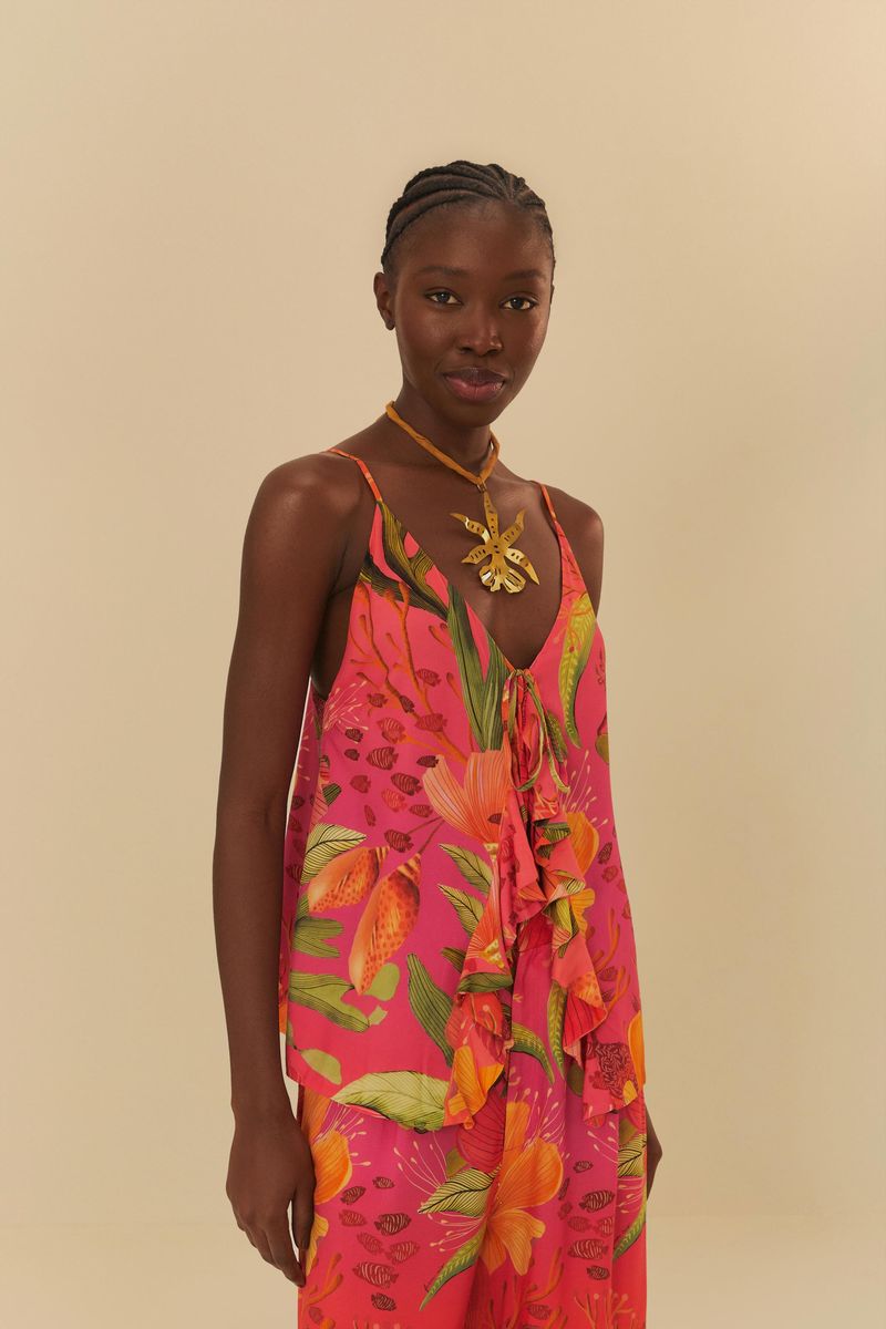 Modelo vistiendo blusa estampada con escote en V y volantes, en fondo rosa vibrante.