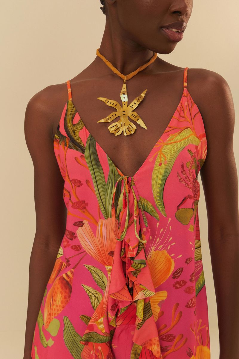 Close del escote en V de la blusa con detalles de volantes y estampado tropical.
