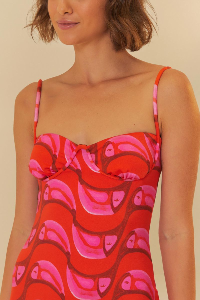 Imagen de un vestido midi con estampado vibrante en tonos de rojo y rosa, con detalle del corsé.