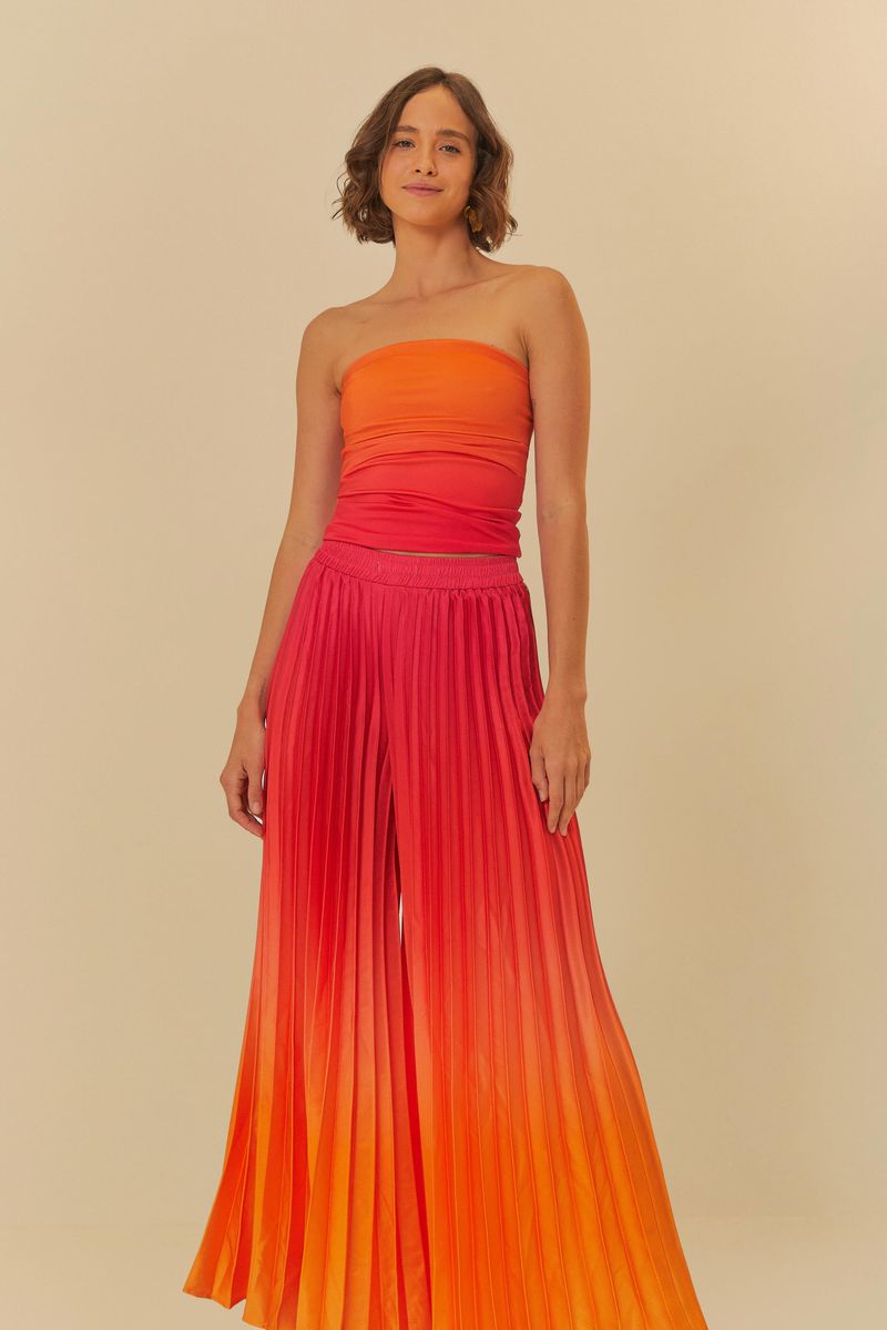 Pantalón largo plisado con efecto degradado en tonos de naranja y rosa, vista frontal.