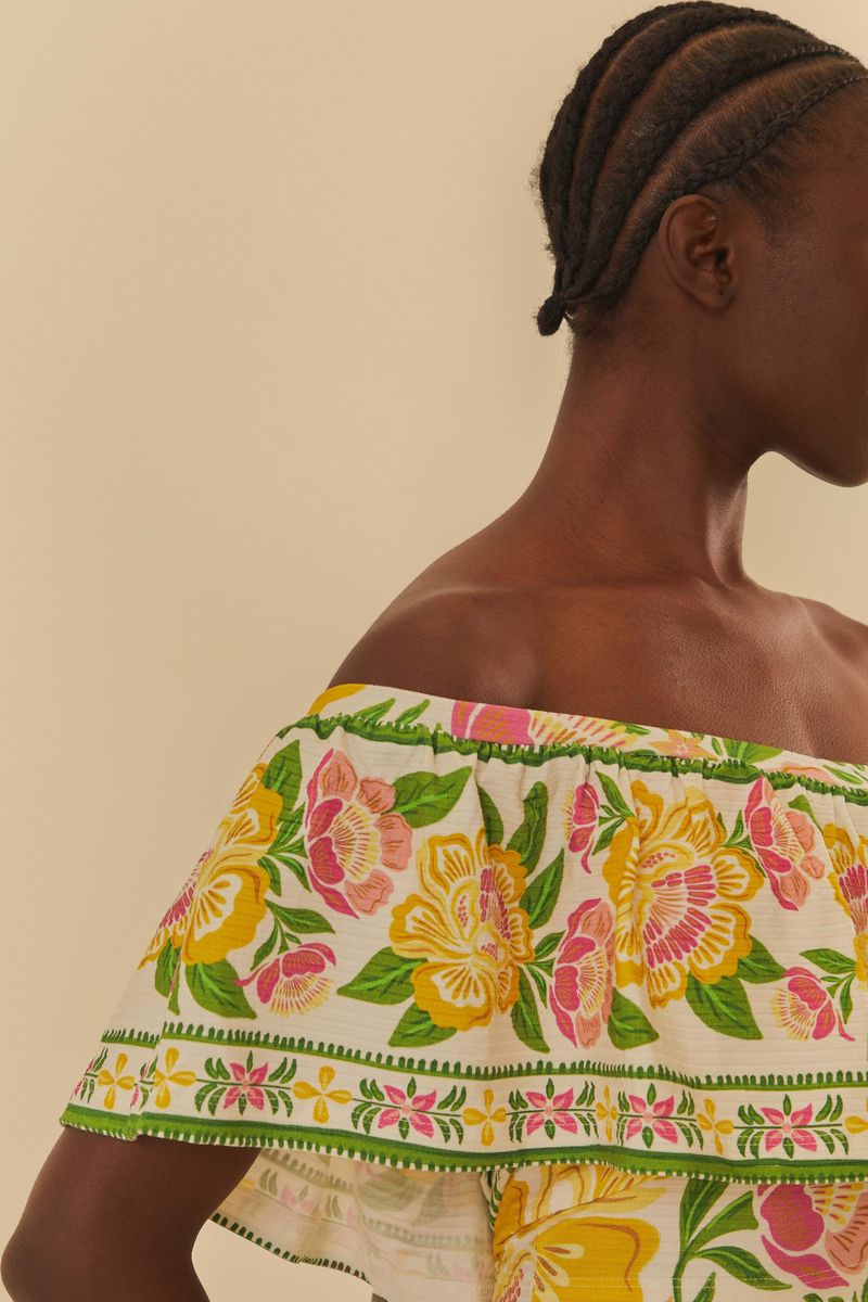 Detalle del tejido floral vibrante de la blusa, mostrando los volantes.