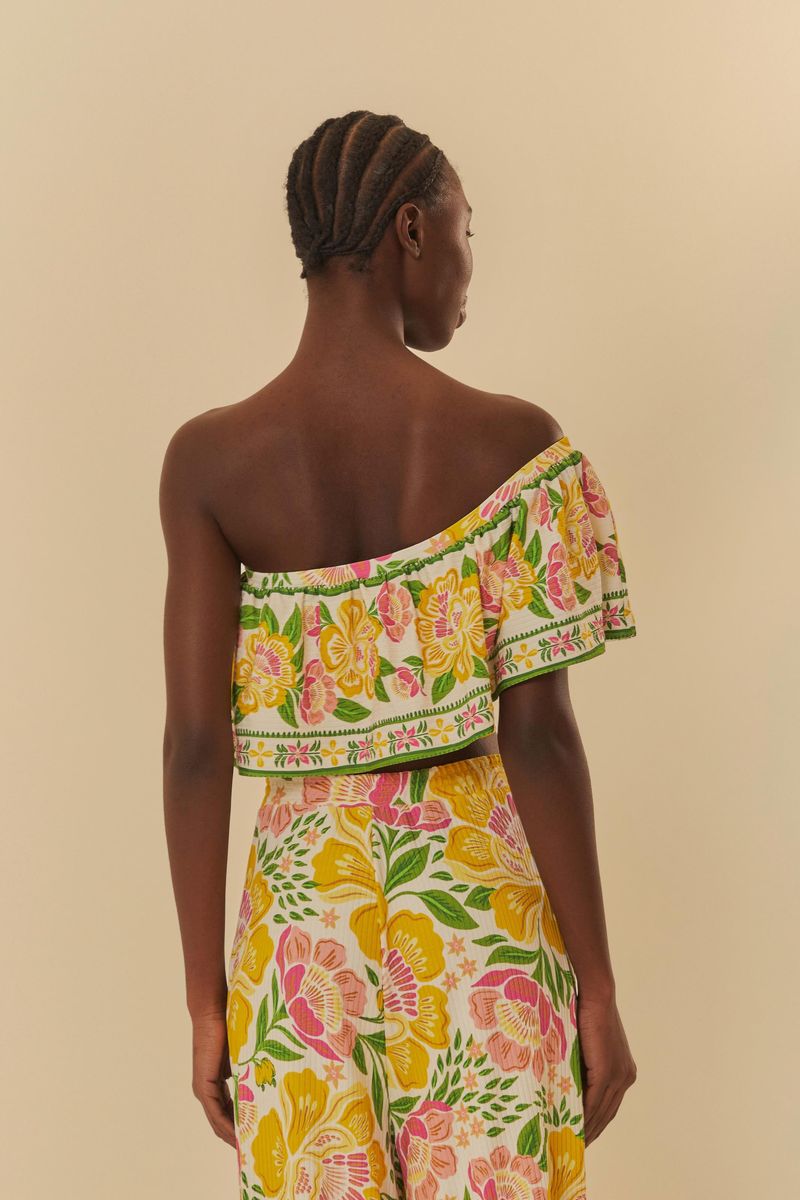 Vista lateral de la blusa floral con diseño de un solo hombro.