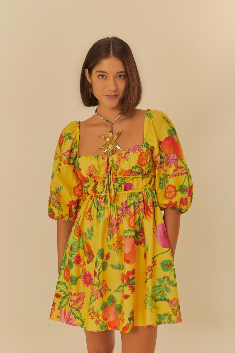 Vestido corto con estampado vibrante de frutas y flores, con mangas abultadas y escote cuadrado con detalles de amarre.