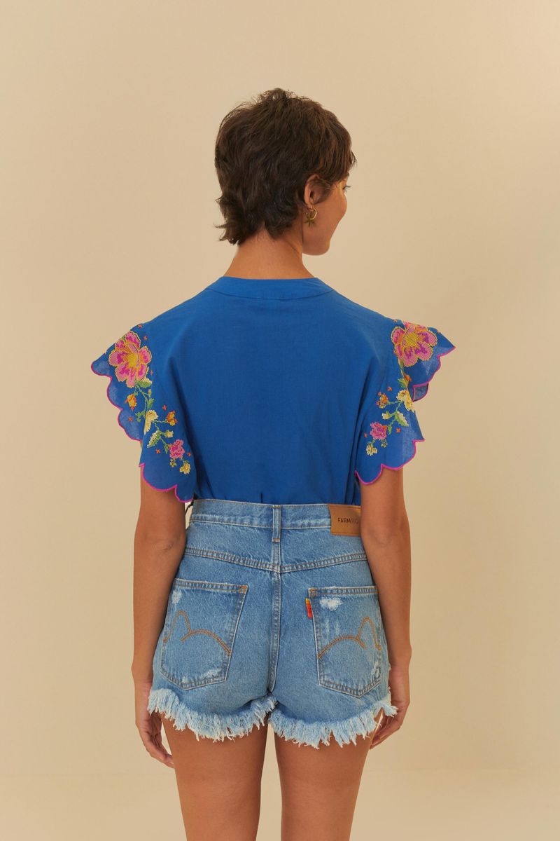Vista posterior del short de jean azul oscuro con cintura alta y bolsillos traseos, combinado con una blusa azul vibrante con estampado floral.