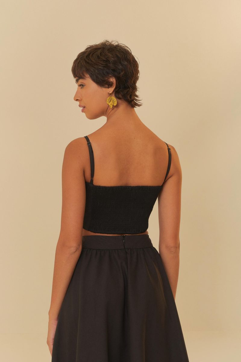 Vista lateral del modelo usando la blusa cropped negra, destacando el diseño de la espalda.