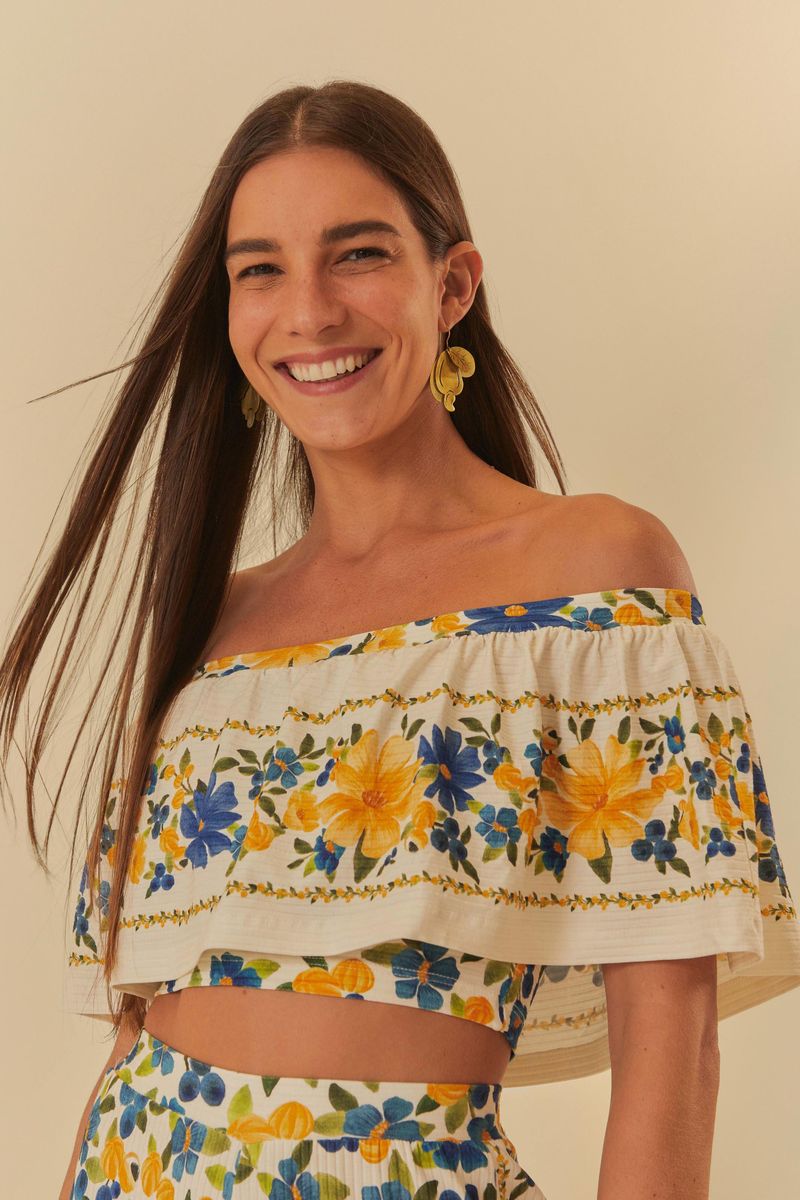 Blusa floral con volantes vista de frente, destacando el escote hombro a hombro y el estampado vibrante.