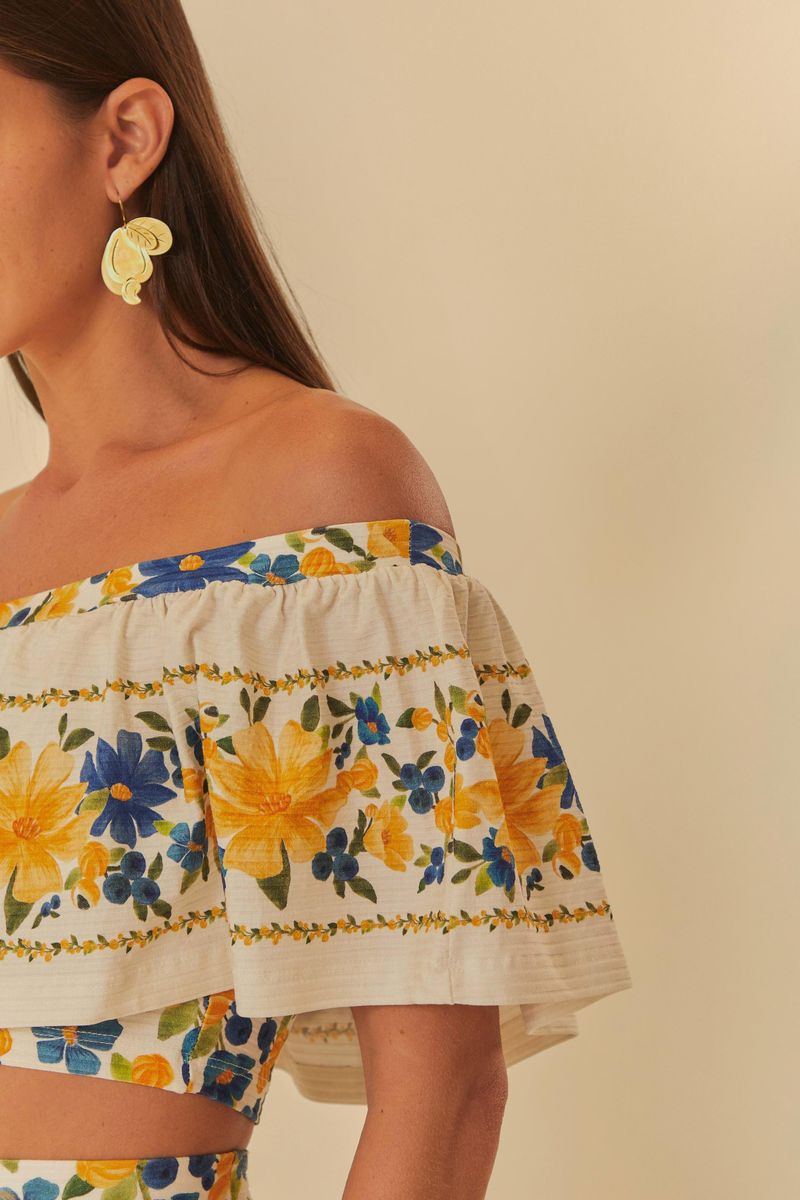 Detalle lateral de la blusa floral con volantes, evidenciando la tela y el estampado.