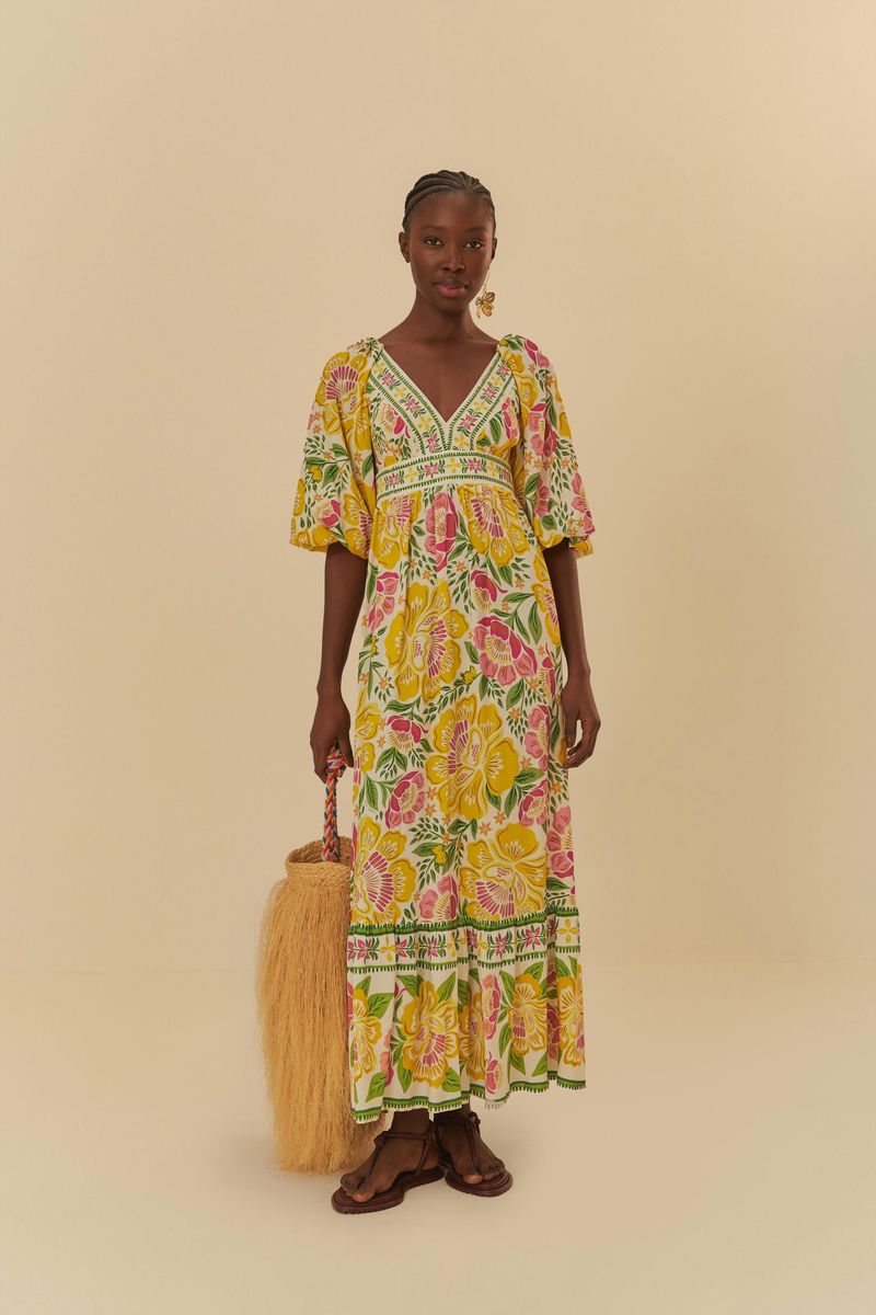 Vista-frontal-de-un-vestido-largo-con-estampado-floral-escote-en-V-y-mangas-cortas-acompañado-de-una-bolsa-de-paja.