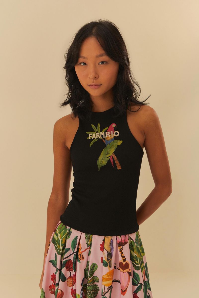 Modelo usando una camiseta negra con estampado de tucano y follaje, combinada con una falda larga estampada.