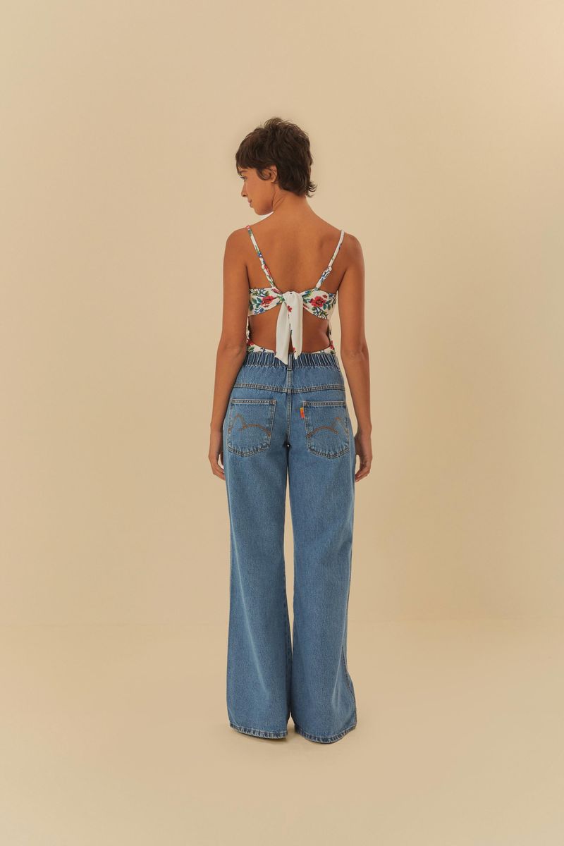 Modelo usando pantalón jeans con recorte y pretina elástica, vista lateral.