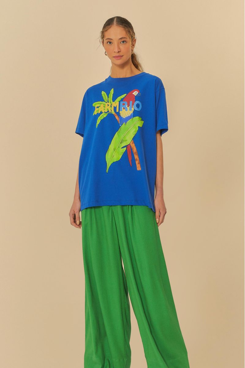 Modelo llevando pantalón verde con camiseta azul estampada, vista lateral.