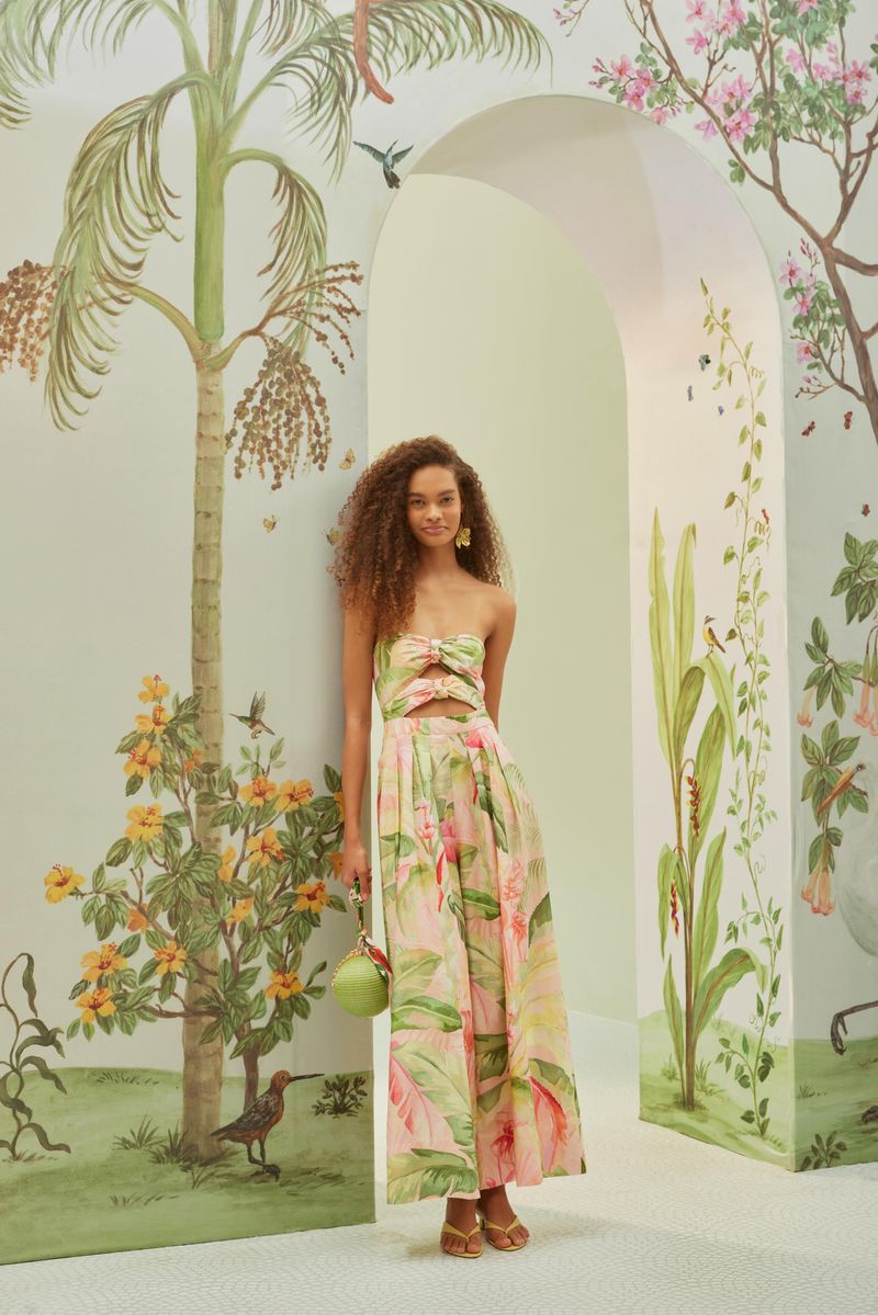 Vestido largo estampado con diseño tropical, sin tirantes, ajustable, presentado en un entorno decorado con motivos naturales.
